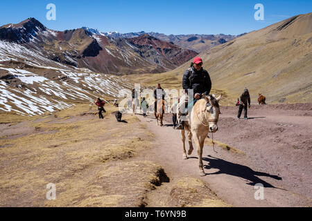 Touristen ein Pferd reiten zu den eindrucksvollen Rainbow Berg in Los Andes von Peru zu erhalten Stockfoto