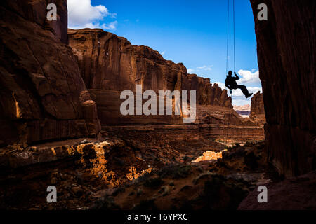 Mann, frei hängend auf einer langen steilen Rappel kommt zum Ende einer Schlucht in der Red Rock Sandstein des südlichen Utah. Absailing über 100 Fuß (30 Meter Stockfoto