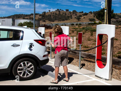 Frau Kraftfahrer Vorbereitung batterie Elektrofahrzeug in Gundagai in New South Wales, Australien zu berechnen Stockfoto