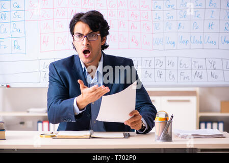 Junge männliche Chemielehrer vor Periodensystem Stockfoto