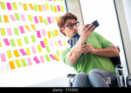 Junger Student in Rollstuhl mit vielen widerstreitenden Prioritäten Stockfoto