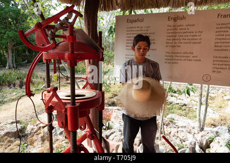 Tour Guide an der Becal Hutmuseum lehrt Besucher wie Panama Hüte mit der herkömmlichen Maschinen vorgenommen werden. Campeche, Mexiko. Stockfoto