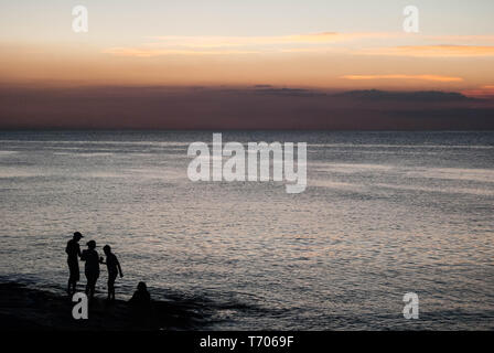 Eine Familie heraus hängen am Ufer bei Sonnenuntergang Stockfoto