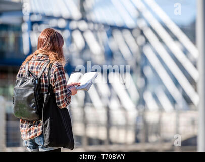 Ein Mädchen ohne Zeit liest ein Buch bei einem Spaziergang auf der Brücke lieber aktiv bewegen, frische Luft atmen, nähren den Intellekt auffüllen Stockfoto