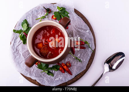 Gulaschsuppe bograch in eine Schüssel geben. Ungarische Gericht. Ansicht von oben auf weißem Hintergrund. Stockfoto