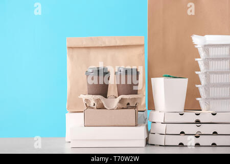 Verschiedene Pakete auf dem Tisch gegen Farbe Hintergrund. Food Delivery Service Stockfoto