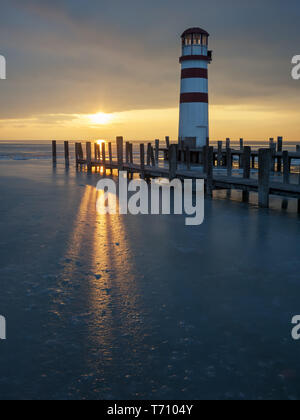 Leuchtturm am Steg am See im Winter Stockfoto