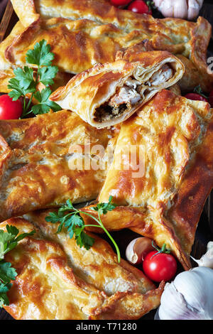 Huhn und Boden Nussbaum gefüllter Blätterteig Borek, gebackener Kuchen geschnitten auf einem Schneidebrett mit Tomatensauce auf einem Tisch, georgische Küche, ver Stockfoto