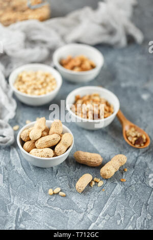 Verschiedene Muttern auf grauem Hintergrund Stockfoto