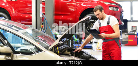 Kfz-Mechaniker in einer Werkstatt die Reparatur eines Fahrzeugs Stockfoto