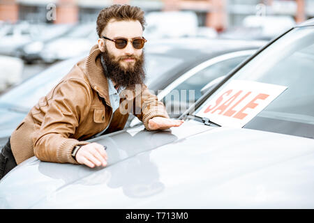 Portrait eines glücklichen Menschen stehen, als Besitzer eines neuen Auto auf dem offenen Gelände des Händlers Stockfoto