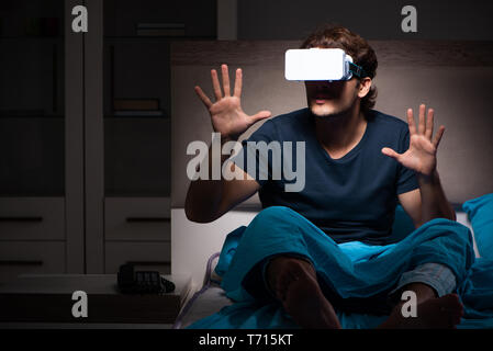 Junger Mann Spielen von Computerspielen in der Nacht im Bett Stockfoto