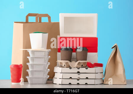 Verschiedene Pakete auf dem Tisch gegen Farbe Hintergrund. Food Delivery Service Stockfoto