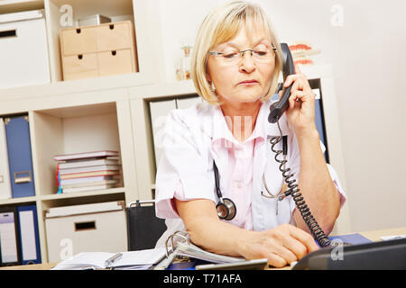 Ärztin Arbeiten am Schreibtisch an der Emergency Medical Service am Telefon Stockfoto
