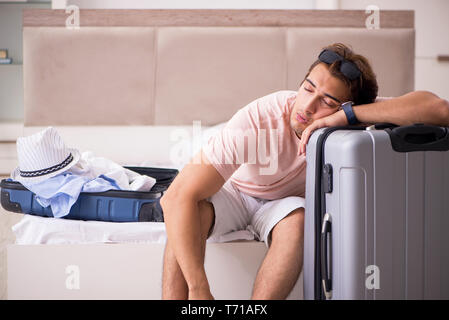 Mann mit Koffer im Schlafzimmer warten auf Reise Stockfoto