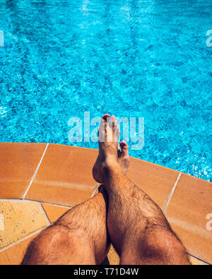 Entspannen am Pool. Man entspannende neben Schwimmbad. Man geniesst die warmen Sommer am Pool. Sonnenbaden am Schwimmbad, mans Stockfoto