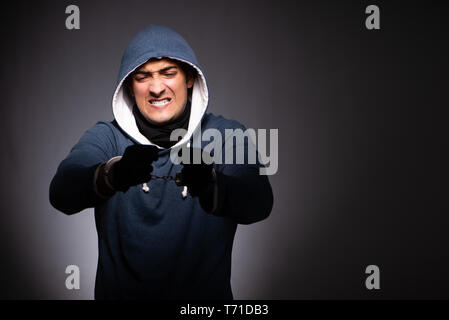 Junge Gangster in der Motorhaube auf grauem Hintergrund Stockfoto