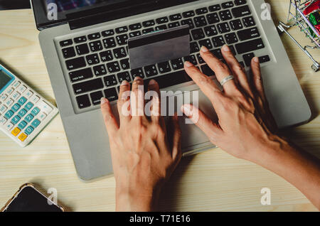 Hände halten eine Kreditkarte und mit einem Laptop auf dem Tisch Stockfoto