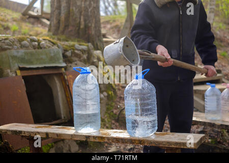 Kaukasische Mann mit Schaufel Zeichnung Wasser aus dem alten Brunnen Stockfoto