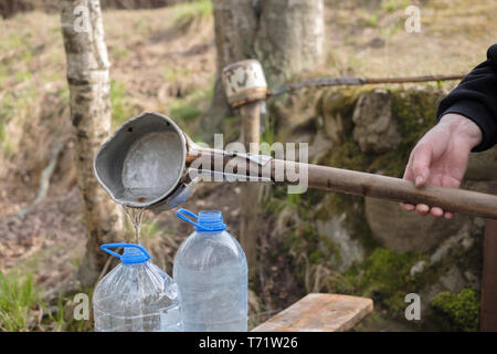 Kaukasische Mann mit Schaufel Zeichnung Wasser aus dem alten Brunnen Stockfoto