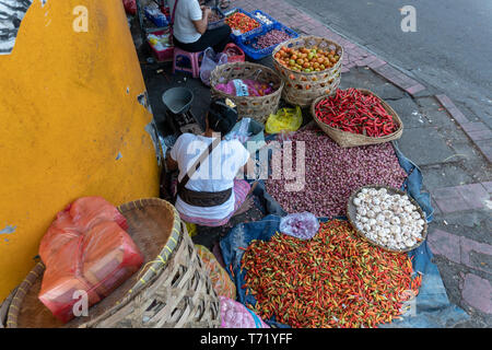 Verkäufer von Gewürzen wie rote Chilischote, rote Zwiebel und Knoblauch sind, verkaufen ihren Handel in einer Ecke des traditionellen Badung Markt Stockfoto