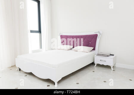 Bett und Nachttisch im hellen Innenraum eines modernen Apartment Stockfoto
