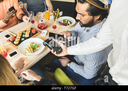 Junge attraktive hinduistischen Mann Bezahlen im Café mit berührungsloser smartphone Zahlung Stockfoto