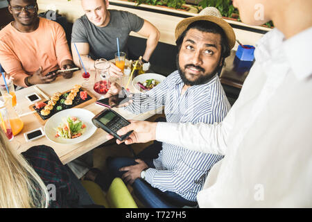 Junge attraktive hinduistischen Mann Bezahlen im Café mit berührungsloser smartphone Zahlung Stockfoto