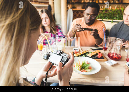 Sind eine Gruppe von Jungen fröhliche Freunde sitzen in einem Cafe, Essen, Trinken Getränke. Freunde nehmen selfies und Bilder zu machen. Stockfoto