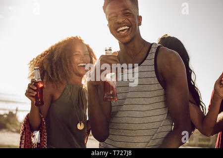 Lächelnden jungen Kerl mit Freunden tanzen im Freien an einem sonnigen Tag. Vielfältige Gruppe von Freunden chillen auf ihr Wochenende. Stockfoto