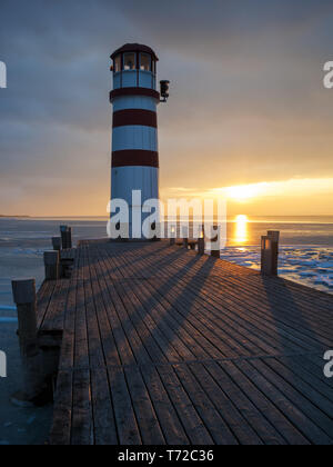 Leuchtturm am Steg am See im Winter Stockfoto