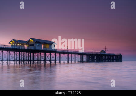 Penarth Pier, auf der South Wales Küste, in der Nähe von Cardiff, bei Sonnenaufgang. Der Himmel ist rot und orange, und das Meer ist glatt Stockfoto