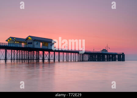 Penarth Pier, auf der South Wales Küste, in der Nähe von Cardiff, bei Sonnenaufgang. Der Himmel ist rot und orange, und das Meer ist glatt Stockfoto