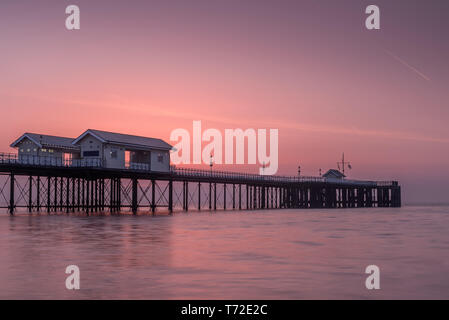 Penarth Pier, auf der South Wales Küste, in der Nähe von Cardiff, bei Sonnenaufgang. Der Himmel ist rot und orange, und das Meer ist glatt Stockfoto