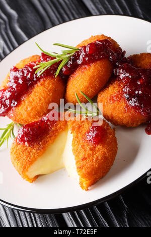 Köstliche Gebackene Camembert paniert mit Preiselbeersoße und Rosmarin closeup auf einem Teller auf den Tisch. Vertikale Stockfoto