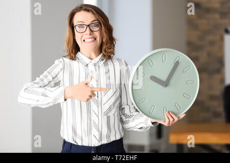 Reife Frau mit Uhr im Amt. Zeit-management Konzept Stockfoto