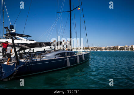 Eine Mannschaft bereitet sich ein Boot im Hafen zu segeln d'Alcudia, Mallorca, Spanien. Stockfoto