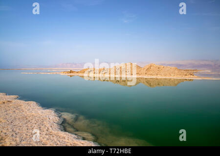 Reflexion von Hügeln in das salzige Wasser des Toten Meeres, unter denen Salz Formationen sichtbar sind Stockfoto