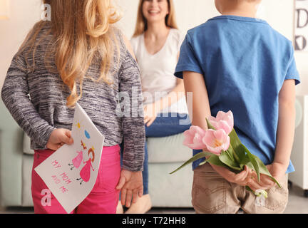 Süße kleine Kinder verstecken Geschenke für Mutter hinter ihrem Rücken Stockfoto