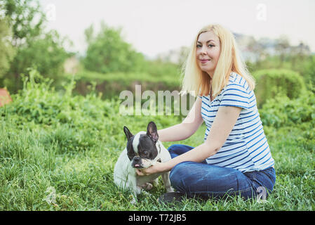 Schwangere Frau mit Hund im Grünen sonnige Natur. Gerne schwangere Frau mit ihr spielen pet im Park Stockfoto