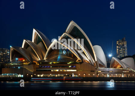 Oper und Innenstadt bei Sonnenuntergang. Beleuchtete Bogen der Brücke in verschwommen Wasser Sydney, New South Wales, Australien widerspiegeln Stockfoto