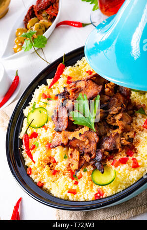 Tajin mit Couscous, Gemüse und Fleisch auf weißem Hintergrund Stockfoto