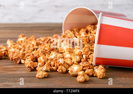 Umgeworfen Tassen mit leckeren caramel Popcorn auf hölzernen Tisch Stockfoto