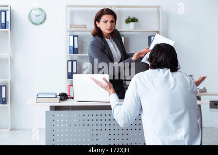 Alte Frau Boss und junge männliche Mitarbeiter im Büro Stockfoto