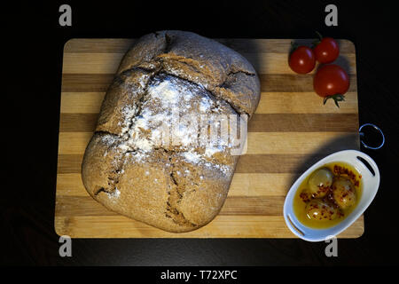 Braunes Brot mit Oliven und Tomaten auf hölzernen Breadboard aus direkt über Stockfoto