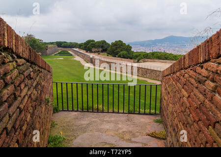 Luftaufnahme von Steinmauern und Rasen des Montjuïc Schloss mit zwei gemauerten Wänden im Vordergrund im bewölkten Tag, Barcelona, Katalonien, Spanien Stockfoto