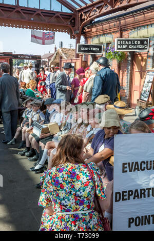 Die Severn Valley Railway, 1940 der Kriegszeit Ereignis, Kidderminster Vintage Railway Station. Jungen & Mädchen (EVAKUIERTEN) im Jahre 1940 die Kleid sitzt auf der Bank warten. Stockfoto