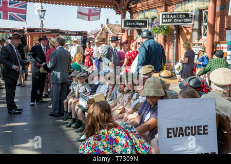 Die Severn Valley Railway, 1940 der Kriegszeit Ereignis, Kidderminster Vintage Railway Station. Jungen & Mädchen (EVAKUIERTEN) im Jahre 1940 die Kleid sitzt auf der Bank warten. Stockfoto