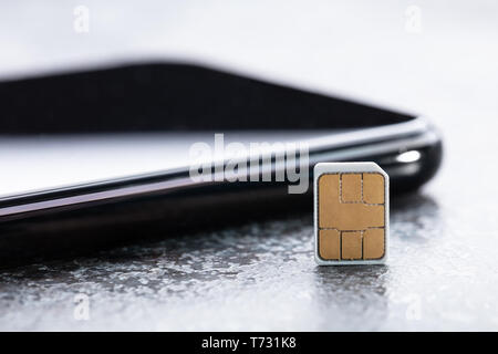 In der Nähe von SIM-Karte und Smartphone auf rauen Hintergrund Stockfoto