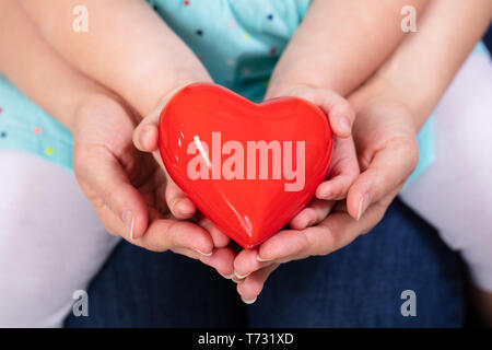 Nahaufnahme der Mutter und Tochter Hand halten roten Herzen Stockfoto